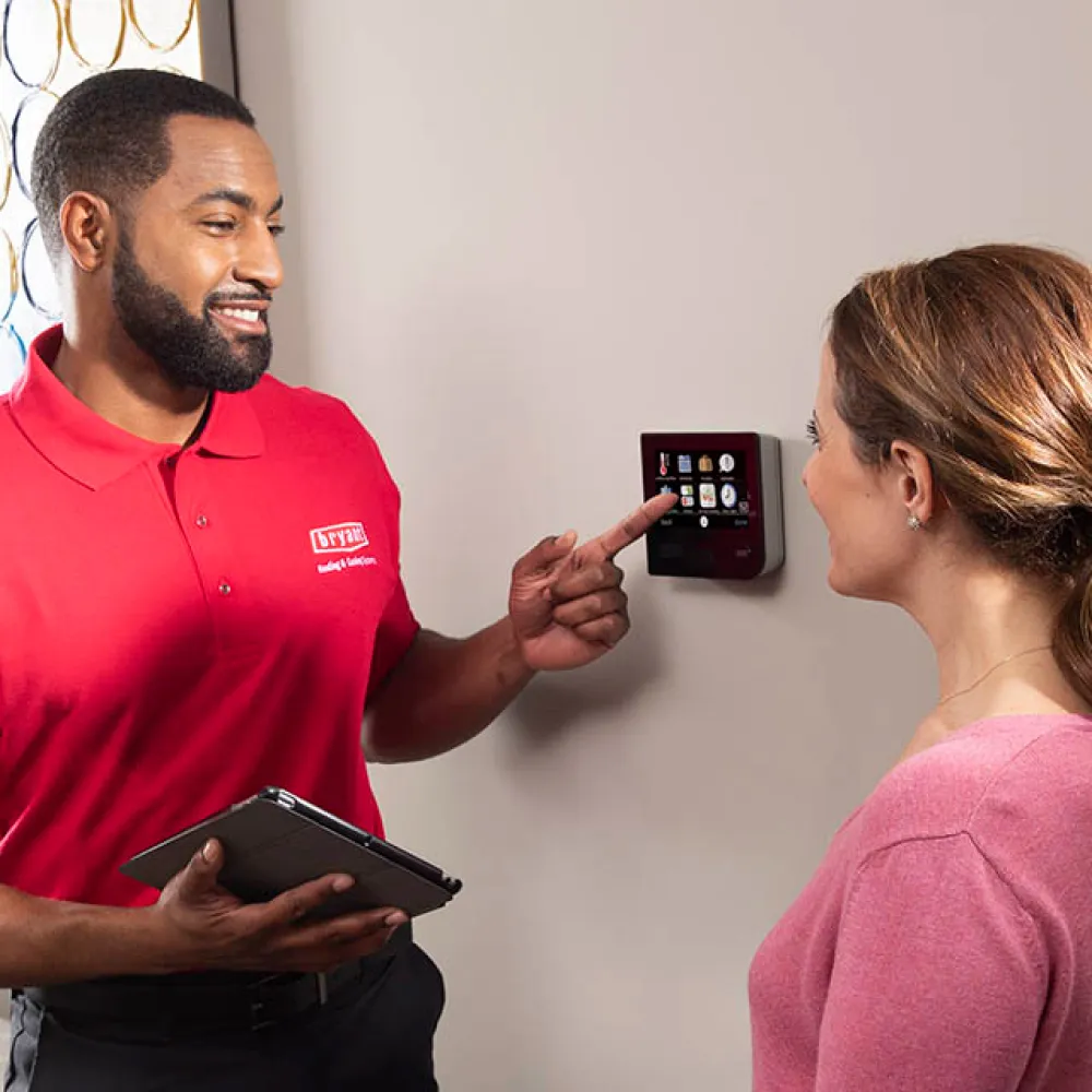 Best HVAC services Sarasota, Bryant air conditioning service tech, showing a WIFI thermostat to client.